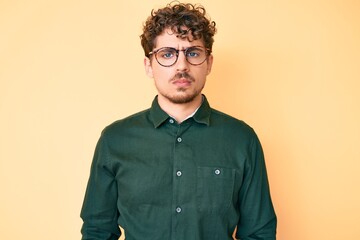 Obraz premium Young caucasian man with curly hair wearing casual clothes and glasses depressed and worry for distress, crying angry and afraid. sad expression.