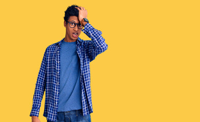 Young african american man wearing casual clothes and glasses surprised with hand on head for mistake, remember error. forgot, bad memory concept.