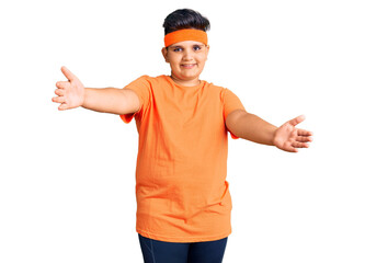 Little boy kid wearing sportswear looking at the camera smiling with open arms for hug. cheerful expression embracing happiness.