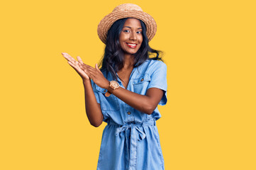 Young indian girl wearing summer hat clapping and applauding happy and joyful, smiling proud hands...