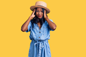 Young indian girl wearing summer hat suffering from headache desperate and stressed because pain...