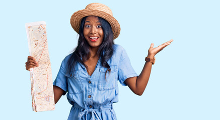 Young indian girl holding city map celebrating victory with happy smile and winner expression with...