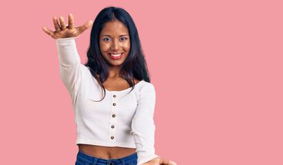 Young indian girl wearing casual clothes looking at the camera smiling with open arms for hug....