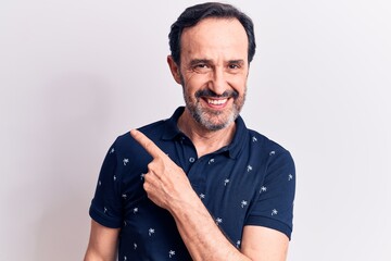 Middle age handsome man wearing casual polo standing over isolated white background smiling cheerful pointing with hand and finger up to the side