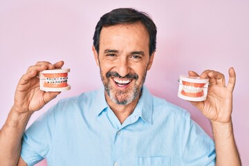 Middle age hispanic man holding orthodontic smiling and laughing hard out loud because funny crazy joke.