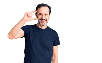 Middle age handsome man wearing casual t-shirt smiling and confident gesturing with hand doing small size sign with fingers looking and the camera. measure concept.