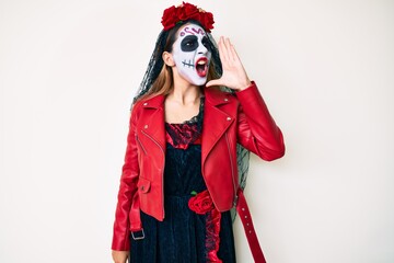 Woman wearing day of the dead costume over white shouting and screaming loud to side with hand on mouth. communication concept.