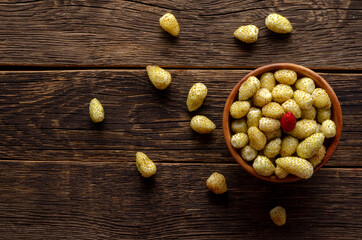 Fresh wild white strawberries on an old wooden