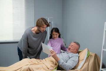 Obraz premium Two people visiting a man in a nurcing home.