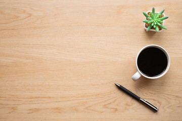Wooden office desk table with coffee and potted plants with a pen. Business and finance concept. Workplace, Flat lay with blank copy space. Top view