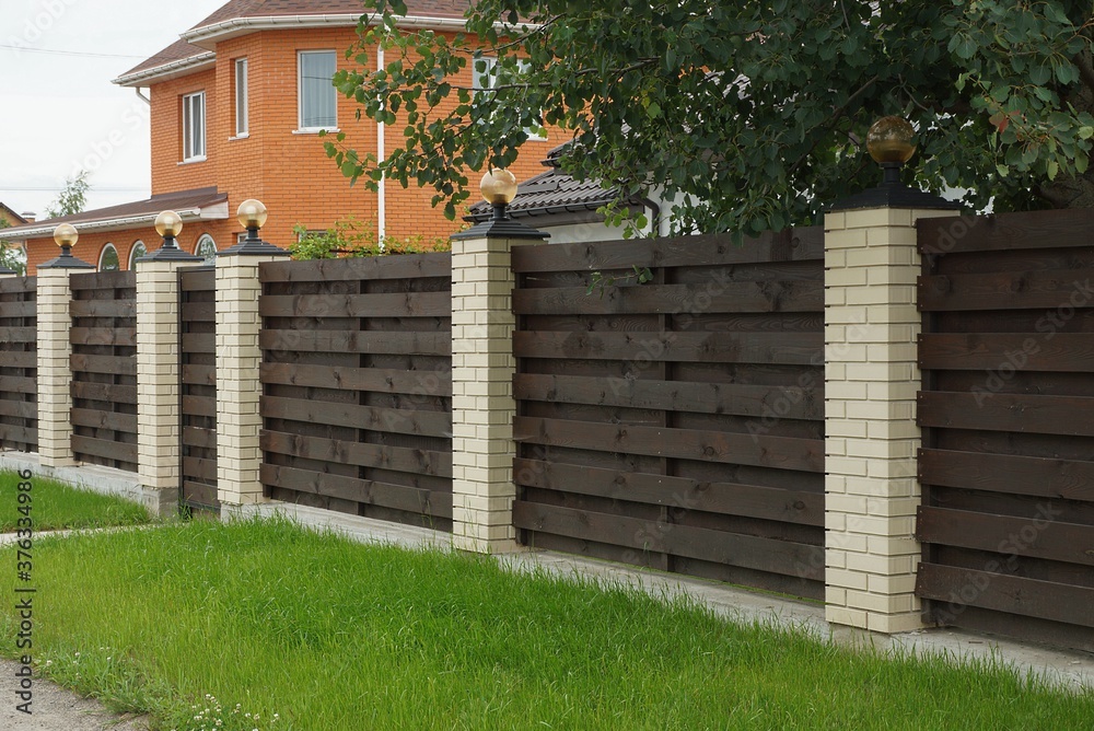 Canvas Prints long brown fence wall made of wooden boards and bricks outdoors