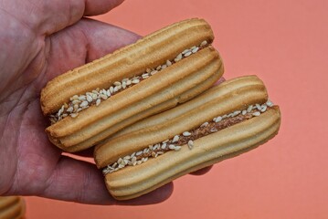 two brown long cookies lie on the palm on a pink background