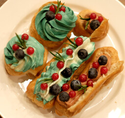 cakes on a plate - cupcakes and eclairs, close up