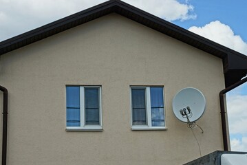 brown loft of a private house with two windows and a white satellite dish