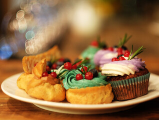 cakes on a plate - cupcakes and eclairs, close up