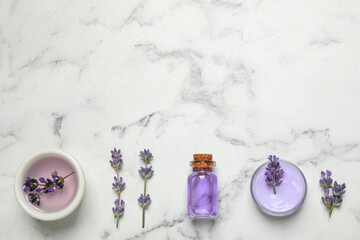 Obraz na płótnie Canvas Cosmetic products and lavender flowers on white marble table, flat lay. Space for text