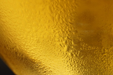 Wet glass of beer, golden color in the dark