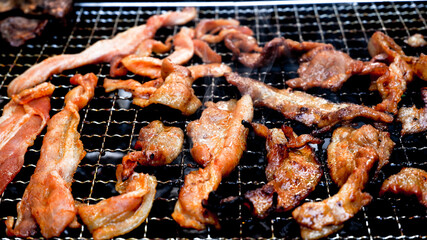 Charcoal grilling of marinated pork strips with smoke effect