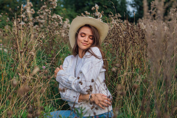 Young beautiful brunette woman sitting on the grass, smiling and touching her hair