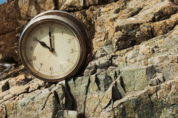 The old round ship's clock on a rock, summer on a rocky sea shore.