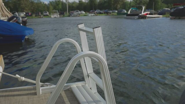 Boat Ladder On A Calm Lake With Parked Vehicles At The Background During Daytime. - Close Up Shot