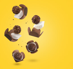 Brigadeiro (Brigadeiro), a Brazilian chocolate candy. Traditional Brazilian handmade chocolate candy. Falling in motion on yellow background