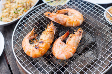 The seafood grilled shrimp buffet is packed with mouthwatering looks and served on a wooden table, stove and grill.