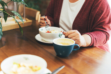 Adult brunette woman in glasses in casual clothing plus size body positive having lunch at the cafe