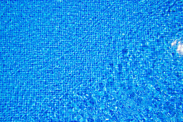 Top view of clear water in a blue tile pool background. Ripple effect