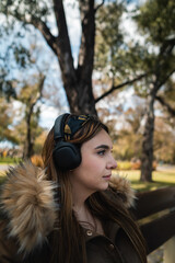 Profile shot of a pretty caucasian woman listening music at park and looking at side. Vertical
