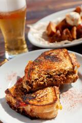 グリルした肉のサンドイッチ（ホットサンド）とグラスビールとフライドポテト