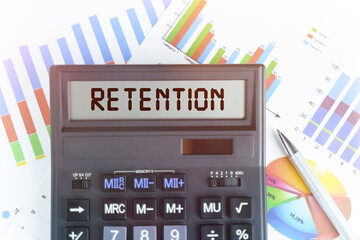 On the table are financial charts and a calculator, on the electronic board of which is written the text - RETENTION