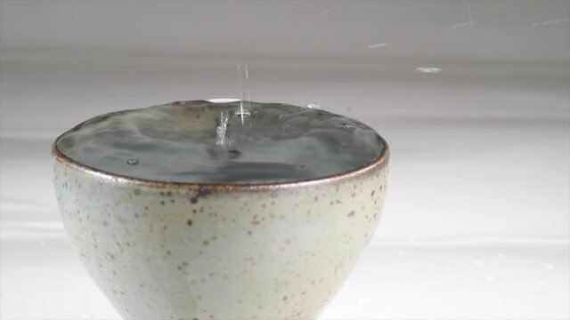 Serving Sake in a ceramic glass in slow motion

