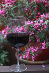 A glass of wine and a vase of flowers on a table