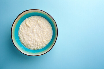 Portion hot of rice porridge in bowl on blue background