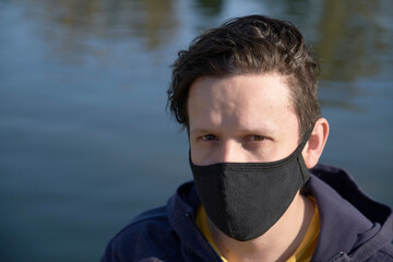 Young man wearing a cloth mask outdoors, in the context of the covid-19 outbreak