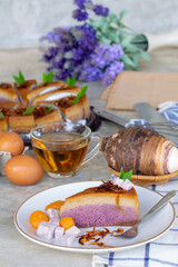 piece of taro chiffon cake topped with Thai taro custard and fried onion on white plate with tea, Concept of dessert and Thai dessert.