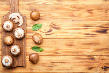 Board with raw mushrooms on wooden table