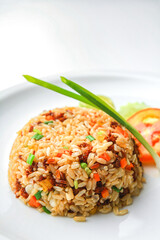 Asian fried rice with egg and vegetable in white ceramic plate on the table in the restaurant. Khao Pad popular Asian traditional style. Thai food. Front view