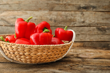 Red bell pepper in wicker bowl on wooden background