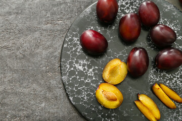 Board with tasty sweet plums on dark background