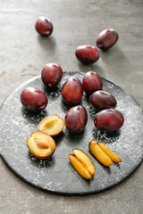 Board with tasty sweet plums on dark background