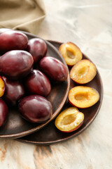 Plates with tasty sweet plums on table