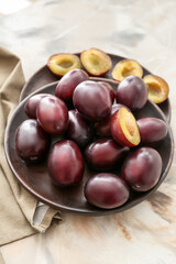 Plates with tasty sweet plums on table
