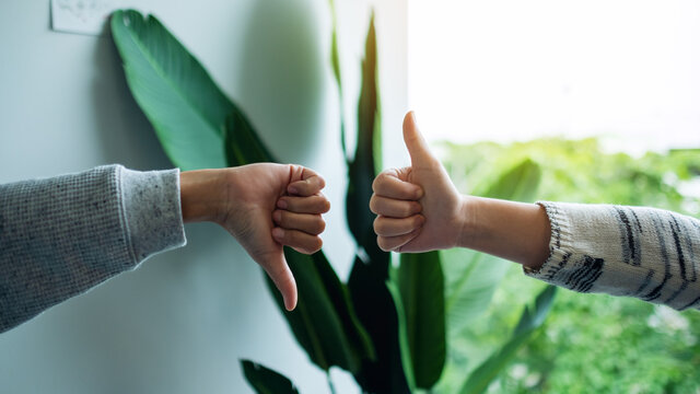 Closeup Image Of Two People Making Thumbs Up And Thumbs Down Hands Sign