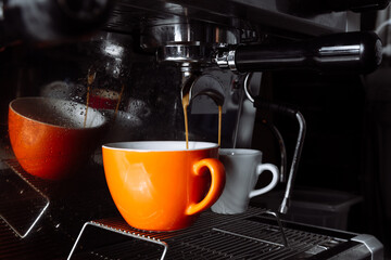 Freshly brewed coffee is poured from the coffee machine into cups . Pouring, beverage.