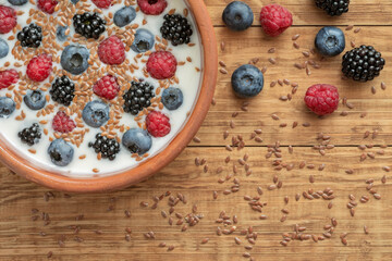 Yogurt with blueberries, raspberries, blackberries, flax seeds in a clay bowl. Served vegetarian dish. Healthy breakfast, healthy food. Background for the menu of restaurants, cafes.