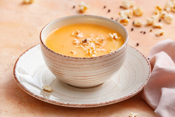 Bowl with tasty popcorn soup on color background