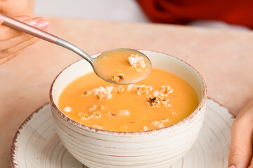 Woman eating tasty popcorn soup from bowl, closeup