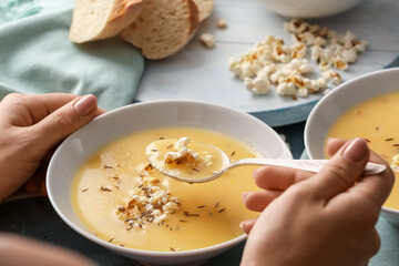 Woman eating tasty popcorn soup from bowl, closeup